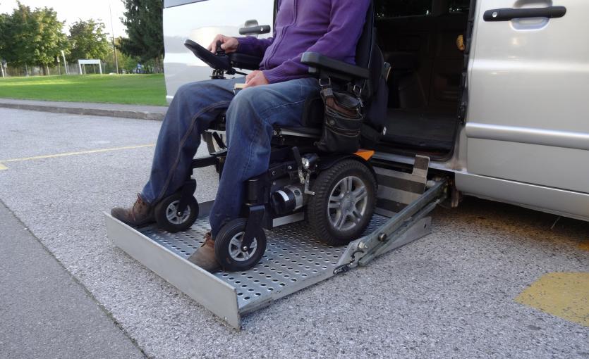 Personne en fauteuil roulant descendant sur la plateforme d'un véhicule adapté